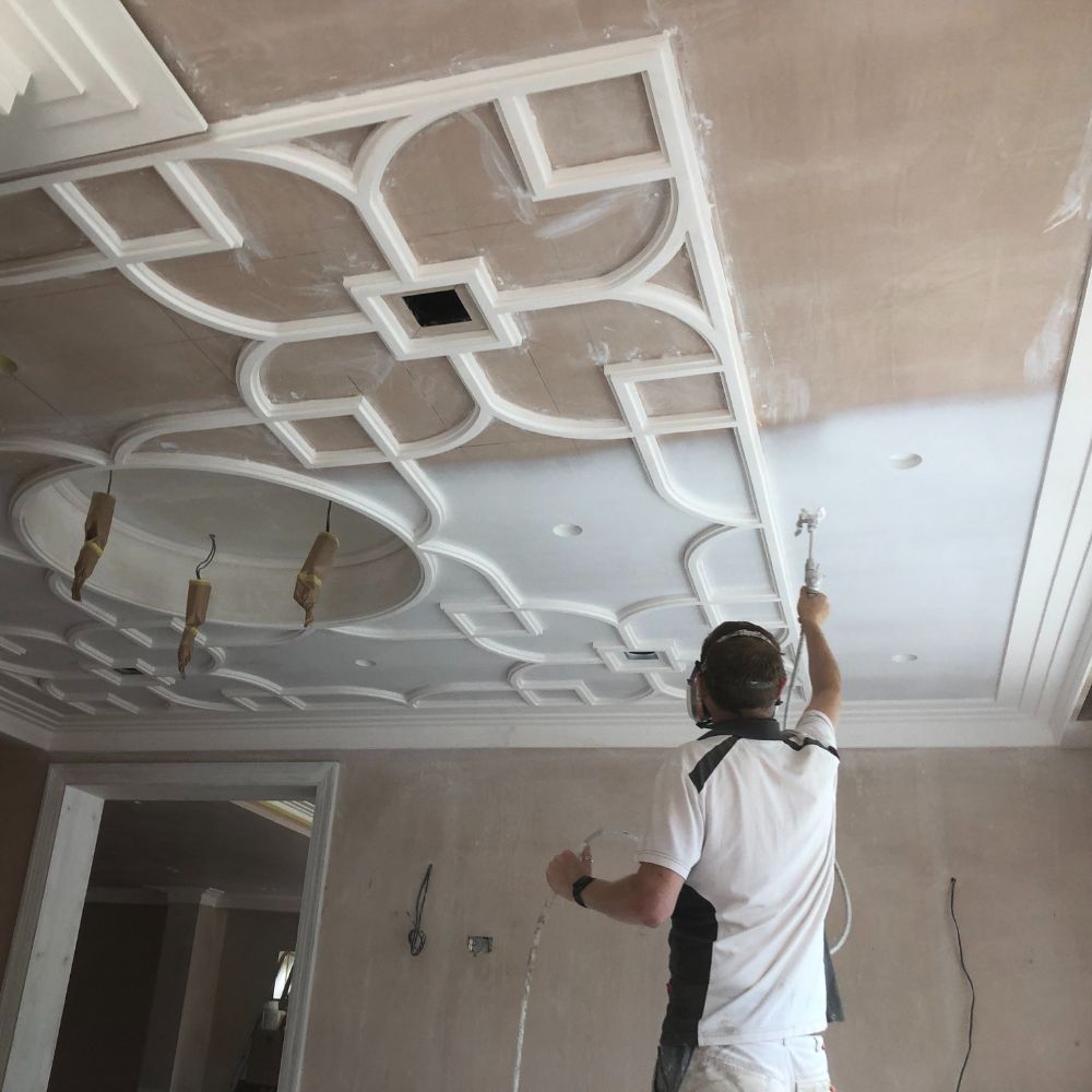 ian from painttech training academy spraying an ornate ceiling with an airless sprayer